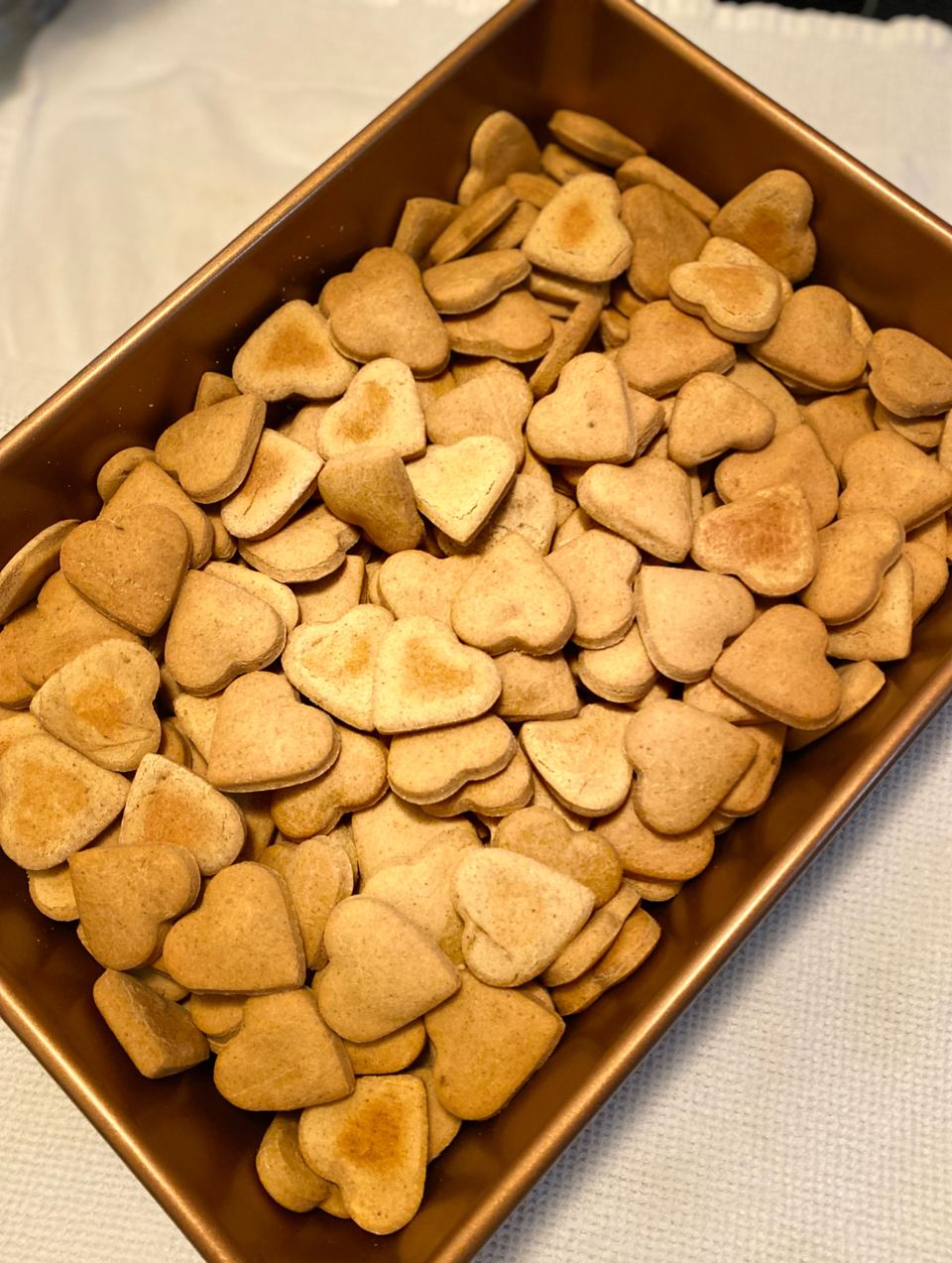 Fresh heart-shaped Nova's Nibbles dog treats cooling on a tray